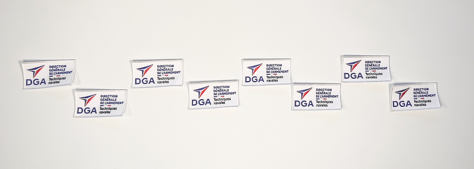 Combinatie van geborduurde badges die op de uniformen van DGA-leden worden genaaid